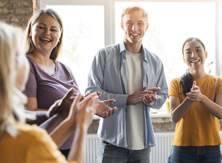 Four people clapping - community and environment - Open GI UK Benefits