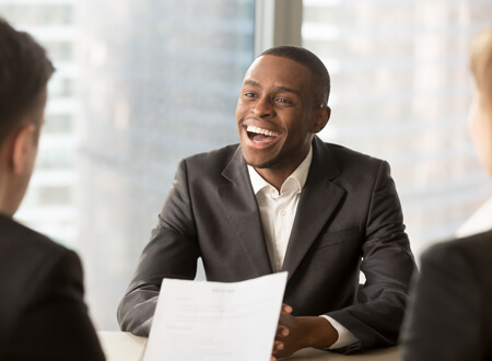 Man laughing at desk - For competitive pay and bonus - Open GI UK Benefits